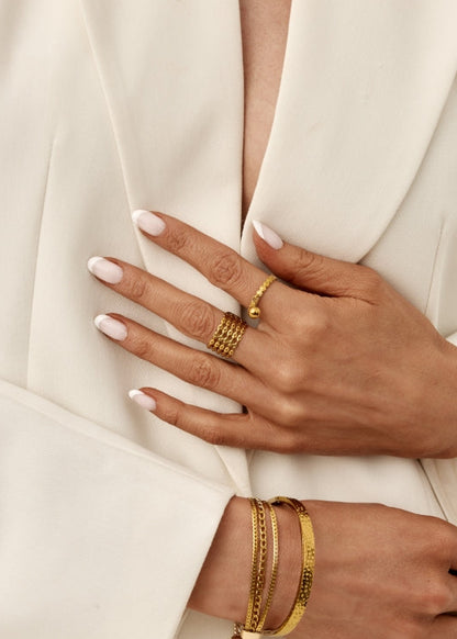 Close-up of hands wearing gold jewelry on a neutral background